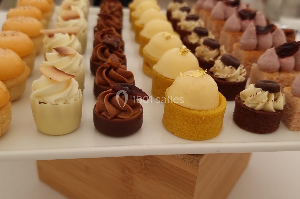 Plateau de mignardises variées disposées en rangées, comprenant des pâtisseries miniatures colorées et décorées.