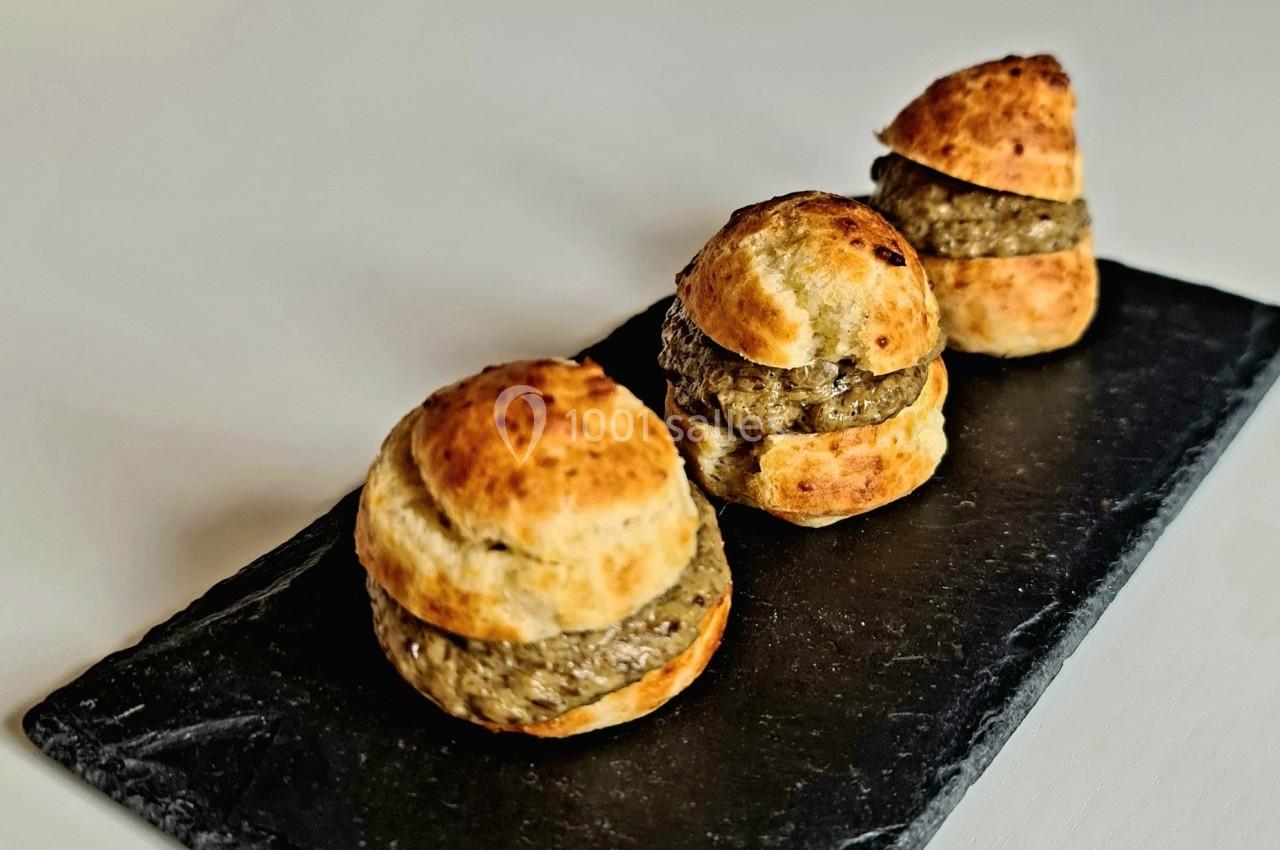 Petits choux garnis d'une mousse ou farce, disposés sur une ardoise noire.