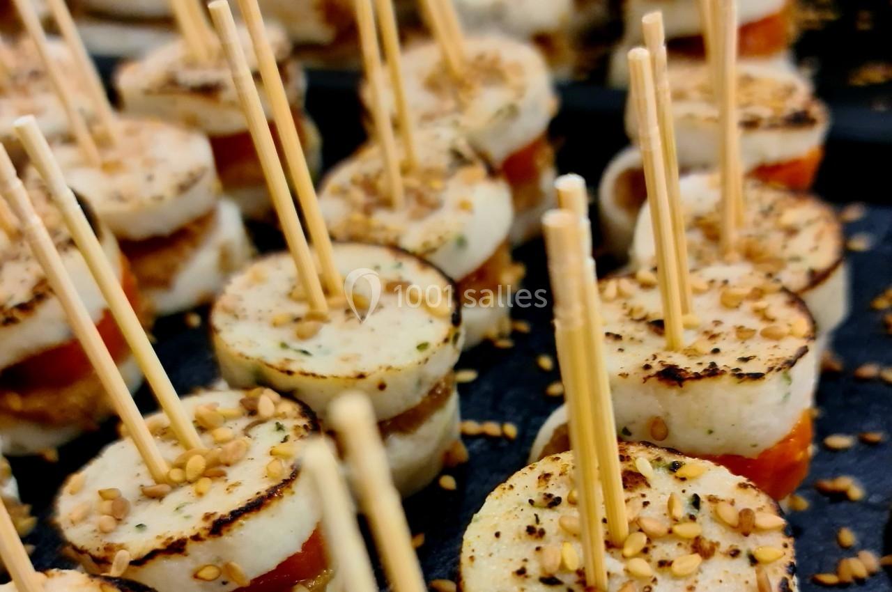 Bouchées apéritives composées de tranches de fromage et de tomate, garnies de sésame et maintenues par des piques en bois.