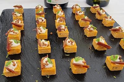Plateau de canapés garnis de crevettes et mousse noire, disposés sur une table devant un sapin illuminé.