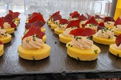 Plateau de canapés garnis de crevettes et mousse noire, disposés sur une table devant un sapin illuminé.