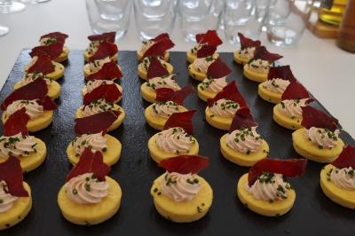 Plateau de canapés garnis de crevettes et mousse noire, disposés sur une table devant un sapin illuminé.