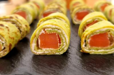 Plateau de canapés garnis de crevettes et mousse noire, disposés sur une table devant un sapin illuminé.