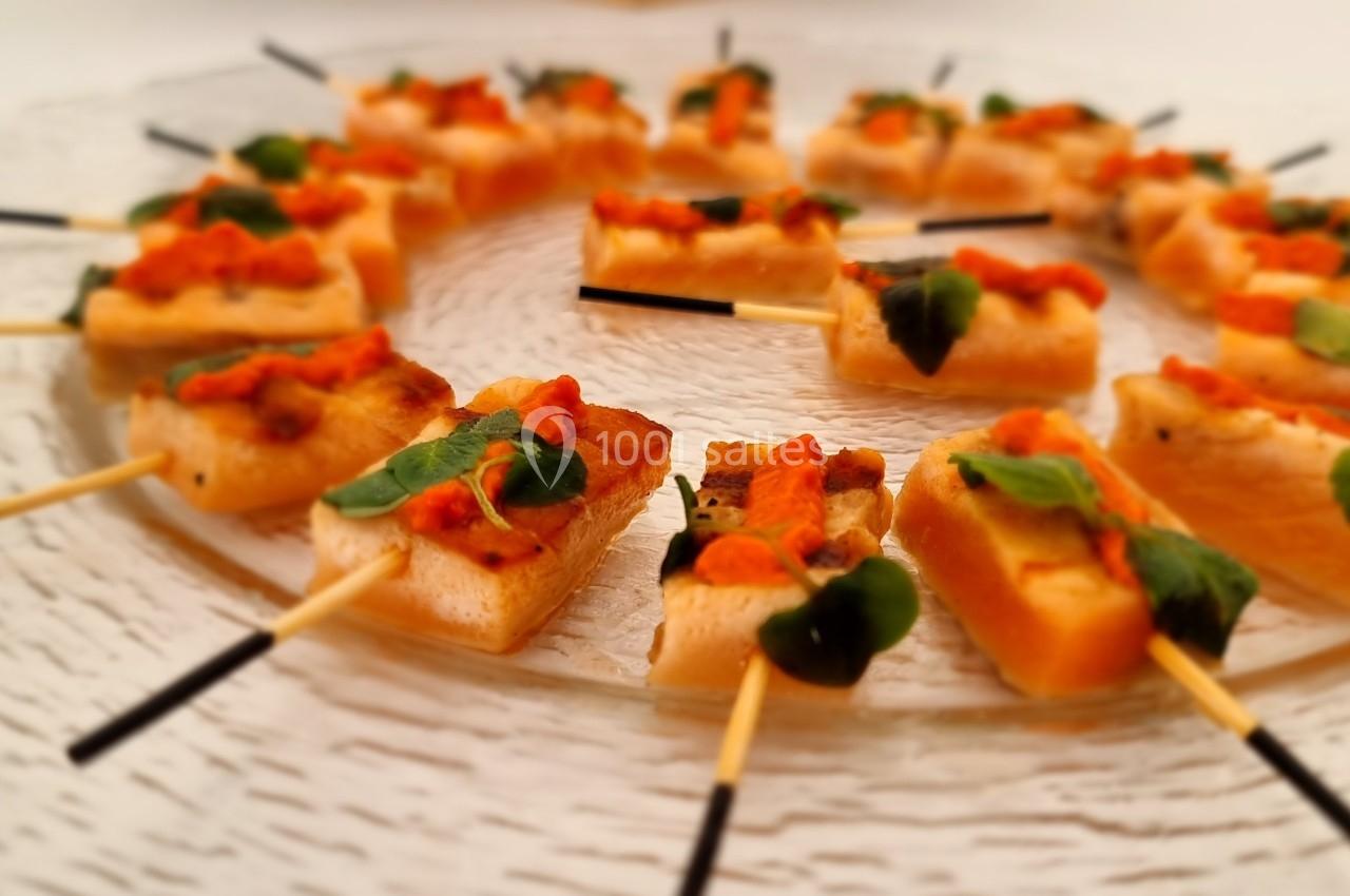 Brochettes apéritives disposées en cercle sur une assiette en verre, garnies de légumes et de feuilles vertes.