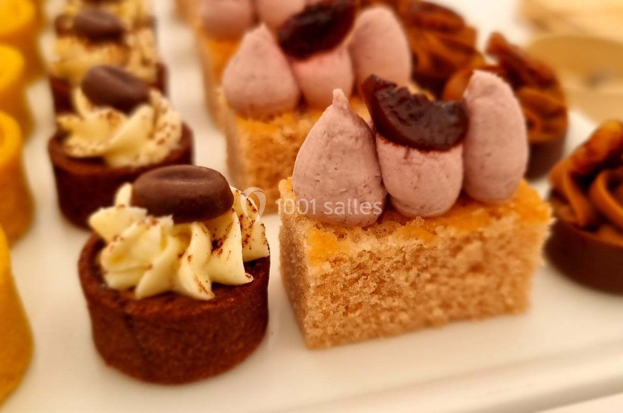 Assortiment de pâtisseries miniatures avec des garnitures variées, dont crème, fruits et chocolat, sur un plateau blanc.