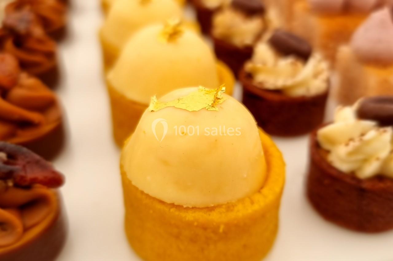 Assortiment de petites pâtisseries colorées, dont une garnie de mousse jaune et décorée de feuille d'or.