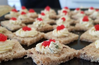 Plateau de canapés garnis de crevettes et mousse noire, disposés sur une table devant un sapin illuminé.