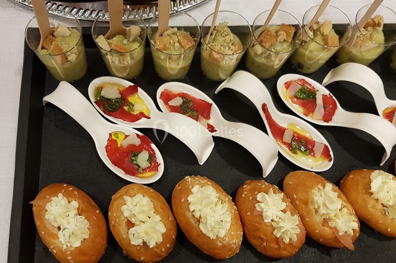 Plateau de bouchées apéritives variées comprenant verrines, cuillères garnies et petits pains au fromage.