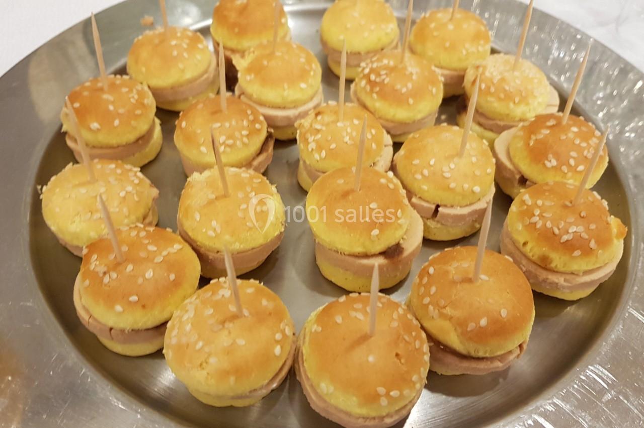 Plateau de mini-burgers garnis, présentés avec des piques en bois, sur un plat rond en métal.