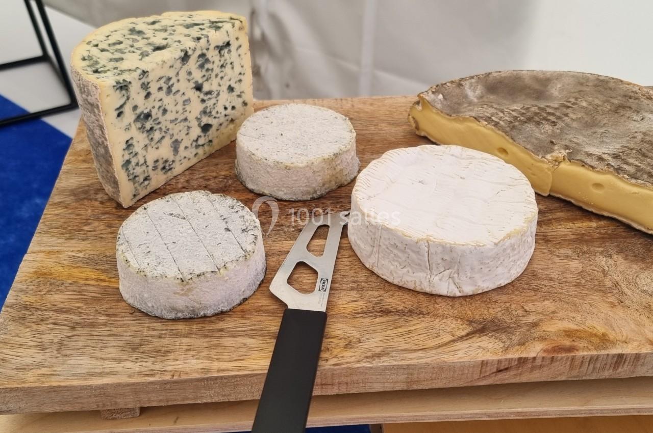 Plateau en bois avec divers fromages, dont un bleu, des fromages ronds et un à croûte épaisse, accompagné d'un couteau.