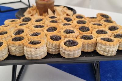 Plateau de canapés garnis de crevettes et mousse noire, disposés sur une table devant un sapin illuminé.