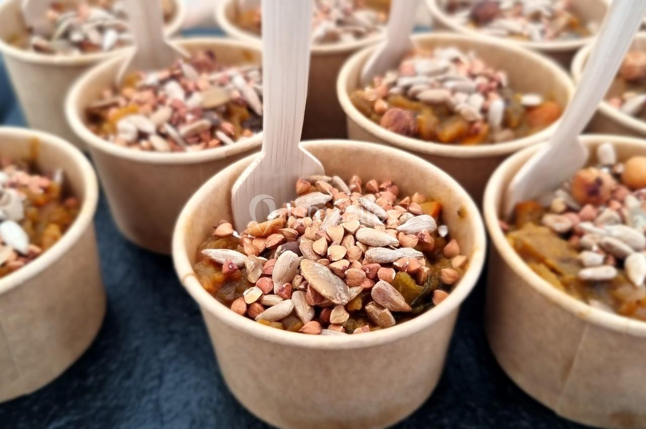 Petits pots en carton remplis de préparation garnie de graines et accompagnés de cuillères en bois.