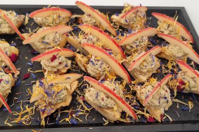 Plateau de canapés garnis de crevettes et mousse noire, disposés sur une table devant un sapin illuminé.