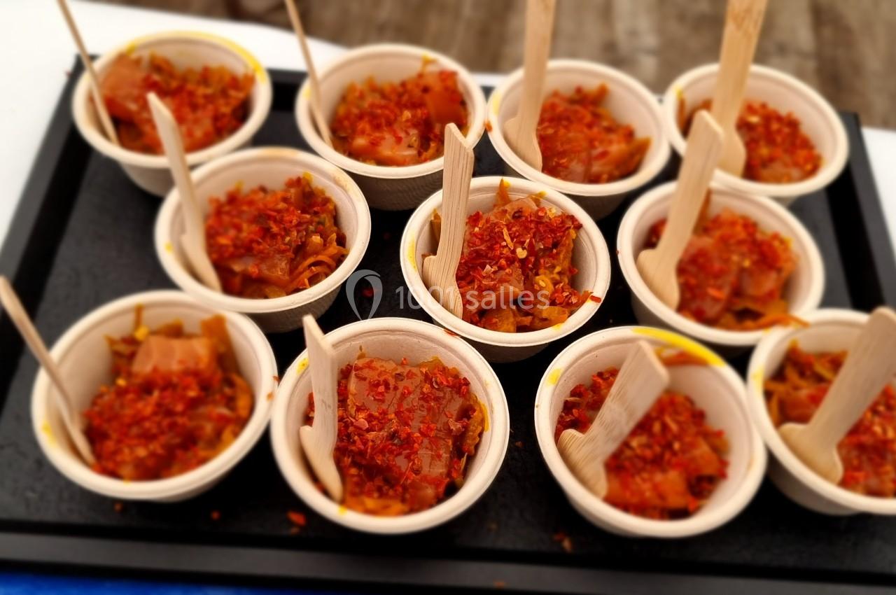 Petits bols en bois remplis de tartare épicé, chacun accompagné d'une fourchette en bois, disposés sur un plateau noir.