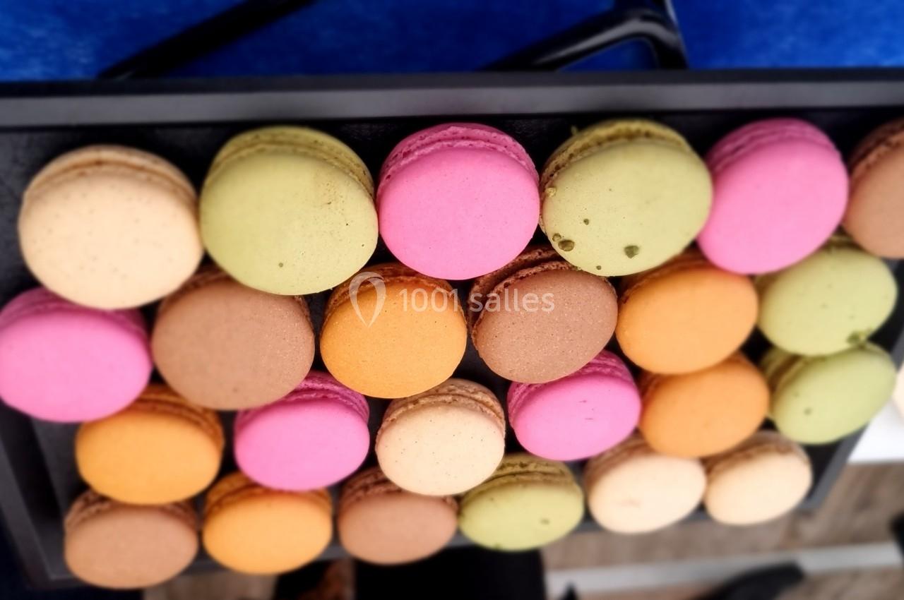 Plateau de macarons colorés disposés en rangées sur une table bleue.