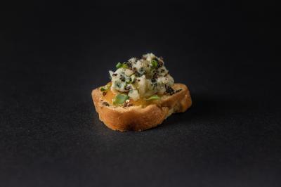 Plateau de canapés garnis de crevettes et mousse noire, disposés sur une table devant un sapin illuminé.