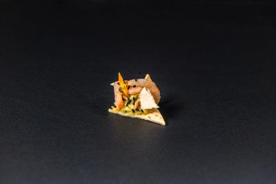 Plateau de canapés garnis de crevettes et mousse noire, disposés sur une table devant un sapin illuminé.