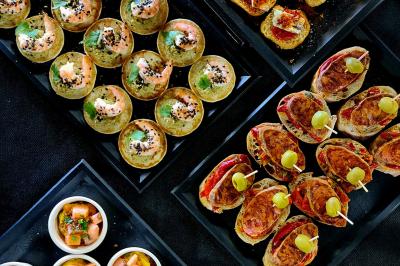 Plateau de canapés garnis de crevettes et mousse noire, disposés sur une table devant un sapin illuminé.