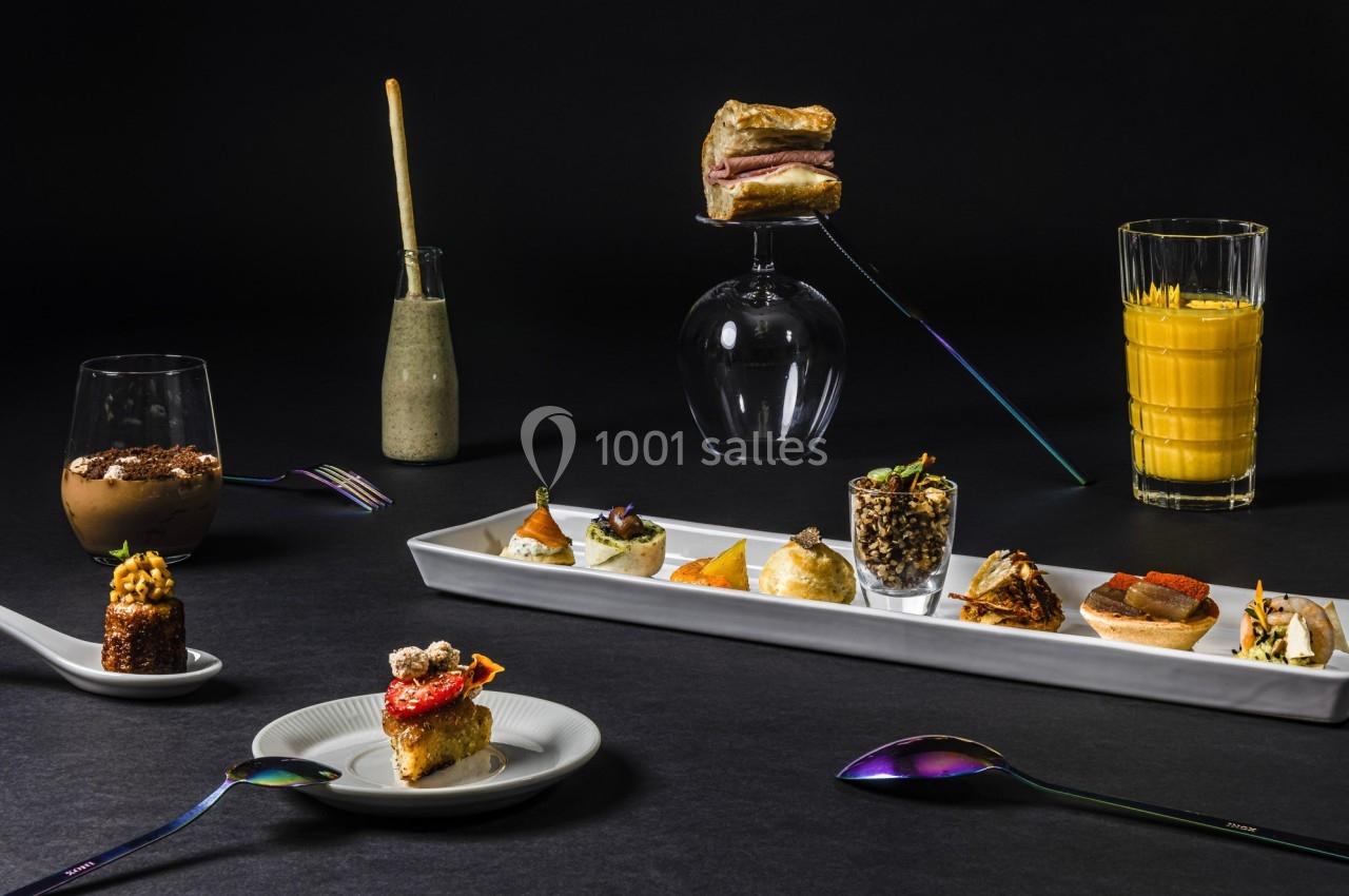 Assortiment de plats gastronomiques et boissons présentés sur une table sombre avec une mise en scène soignée.