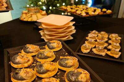 Plateau de canapés garnis de crevettes et mousse noire, disposés sur une table devant un sapin illuminé.