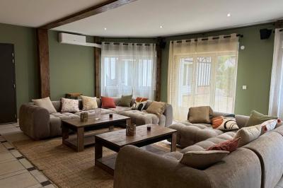 Salle de bain moderne avec douche à paroi vitrée, lavabo rond sur meuble en bois et miroir encadré en rotin.