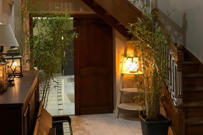 Salle de bain moderne avec douche à paroi vitrée, lavabo rond sur meuble en bois et miroir encadré en rotin.