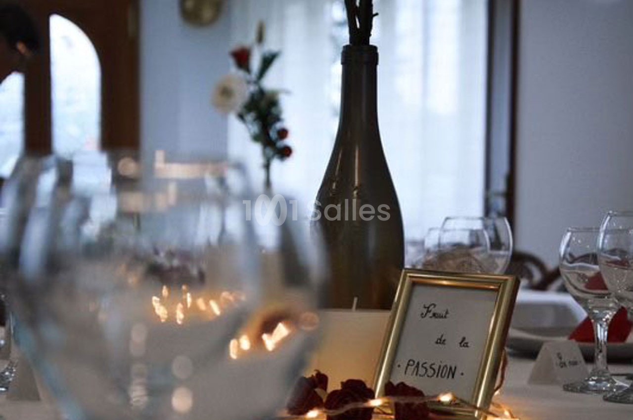 Centre de table avec bouteille décorative, cadre contenant l'inscription ’Fruit de la PASSION’ et pétales rouges.