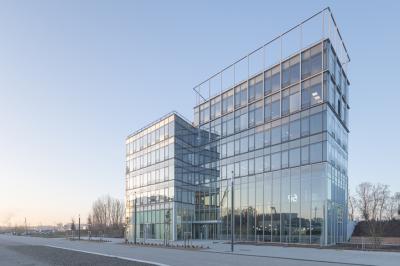 Espace de coworking lumineux avec des plantes, des tables, des chaises et des personnes discutant près d'une kitchenette.