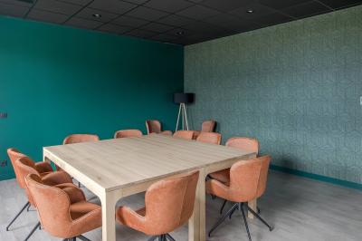 Salle moderne avec tables hautes, chaises rouges, bar en arrière-plan et éclairage suspendu dans un décor industriel.