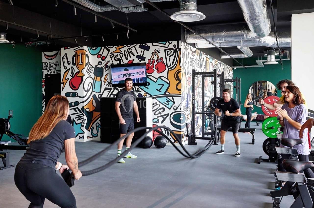 Des personnes s'entraînent dans une salle de sport moderne avec des équipements et des décorations murales colorées.
