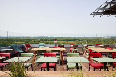 Chambre d'hôtel avec lit double, salle de bain attenante à carreaux rouges et décoration murale colorée.