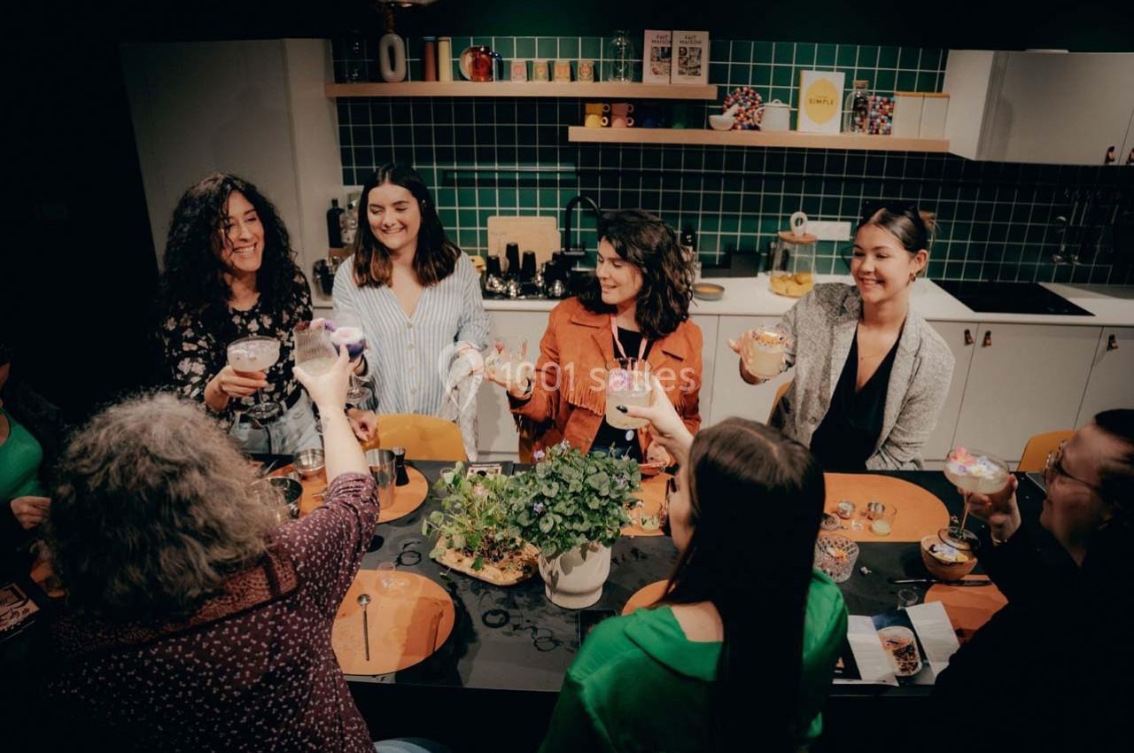 Un groupe de personnes souriantes trinque autour d'une table dans une cuisine moderne et conviviale.