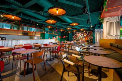 Chambre d'hôtel avec lit double, salle de bain attenante à carreaux rouges et décoration murale colorée.