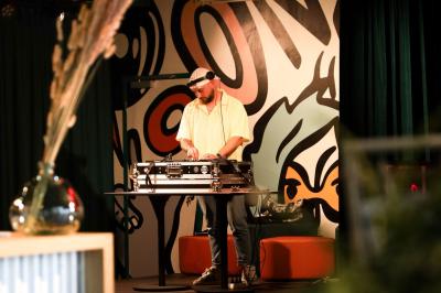 Chambre d'hôtel avec lit double, salle de bain attenante à carreaux rouges et décoration murale colorée.