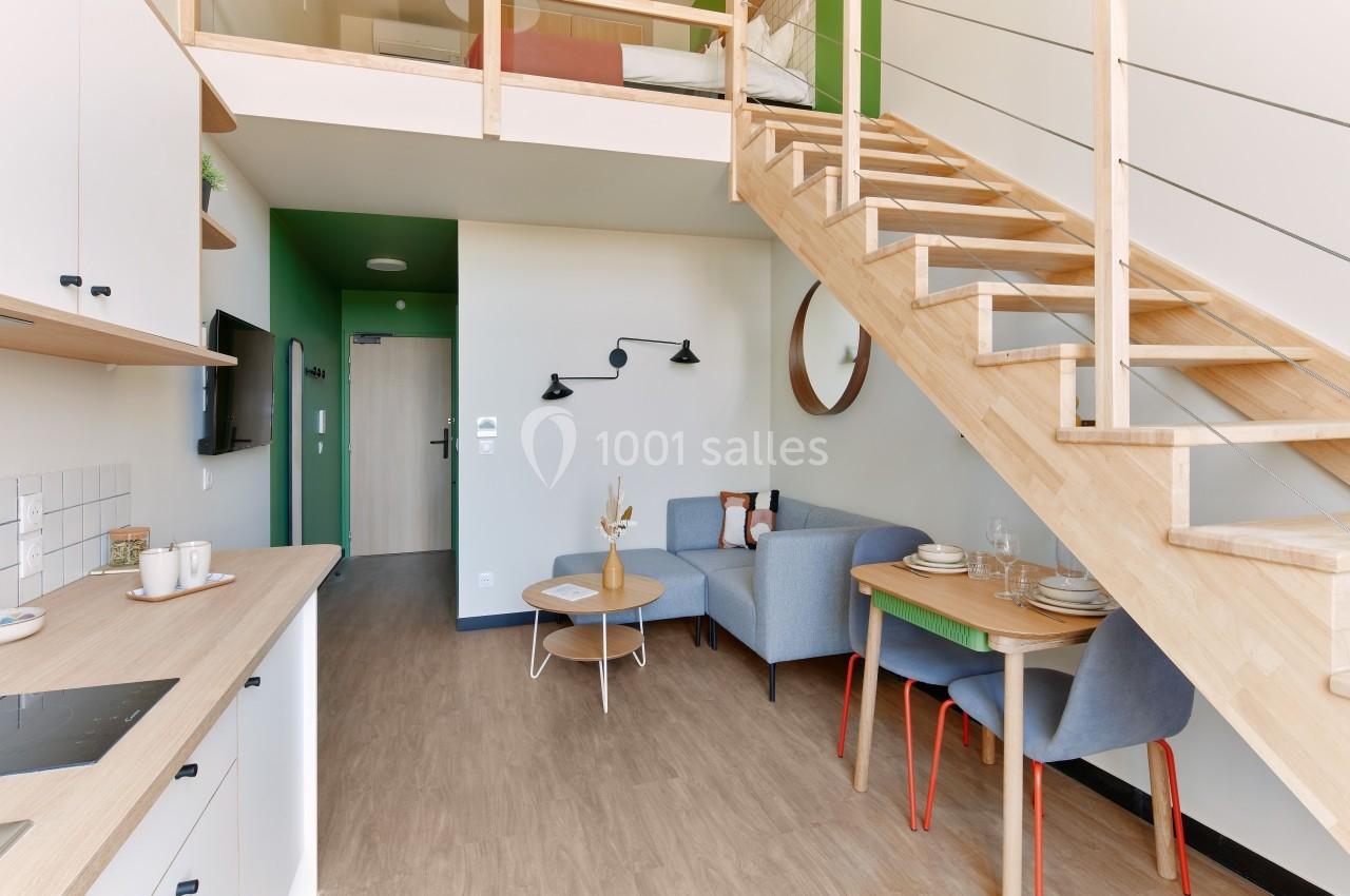 Vue d'un intérieur lumineux avec mezzanine, salon, coin repas et cuisine ouverte au design moderne et épuré.