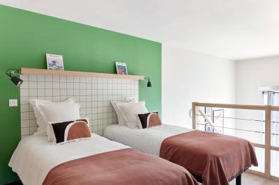 Chambre d'hôtel avec lit double, salle de bain attenante à carreaux rouges et décoration murale colorée.