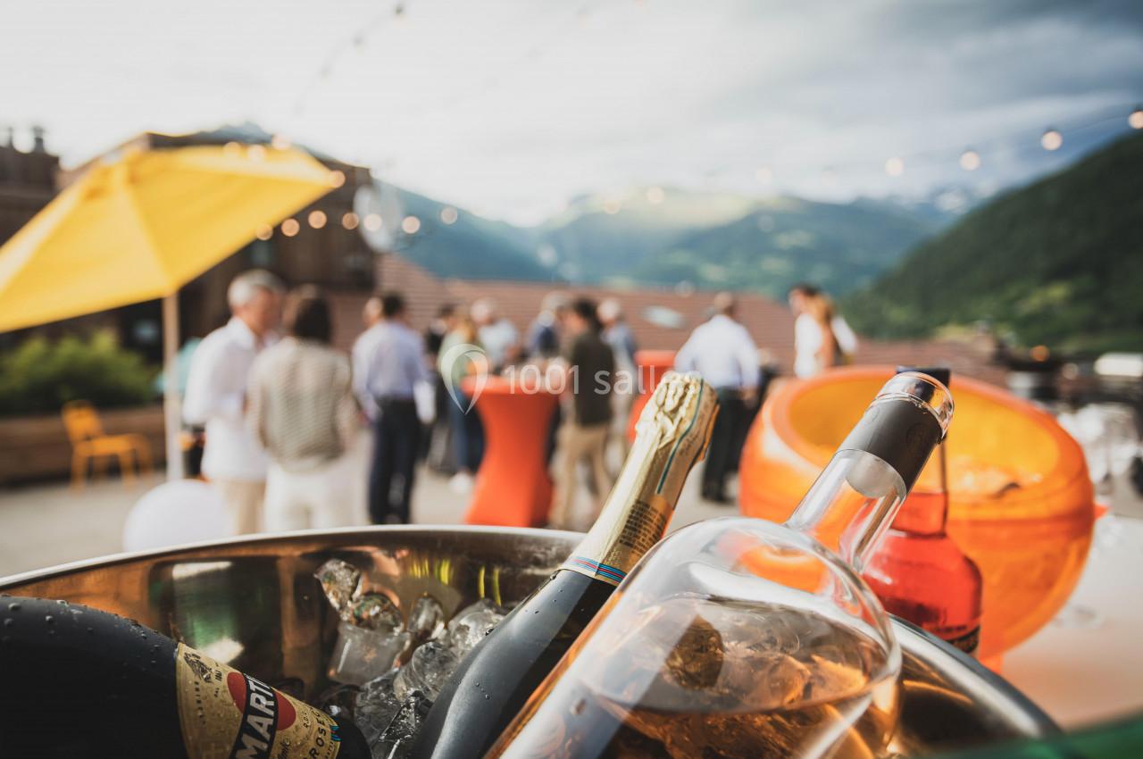 Des bouteilles de vin et de champagne dans un seau à glace au premier plan, avec un groupe de personnes en arrière-plan.
