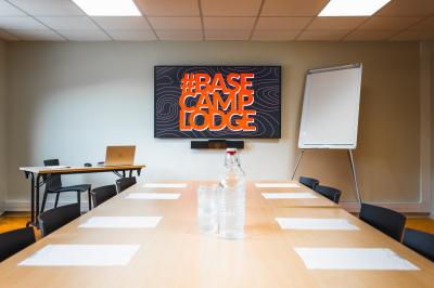 Un groupe de musiciens joue sur scène devant un écran affichant le logo et le slogan ’Base Camp Lodge’.