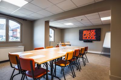 Un groupe de musiciens joue sur scène devant un écran affichant le logo et le slogan ’Base Camp Lodge’.