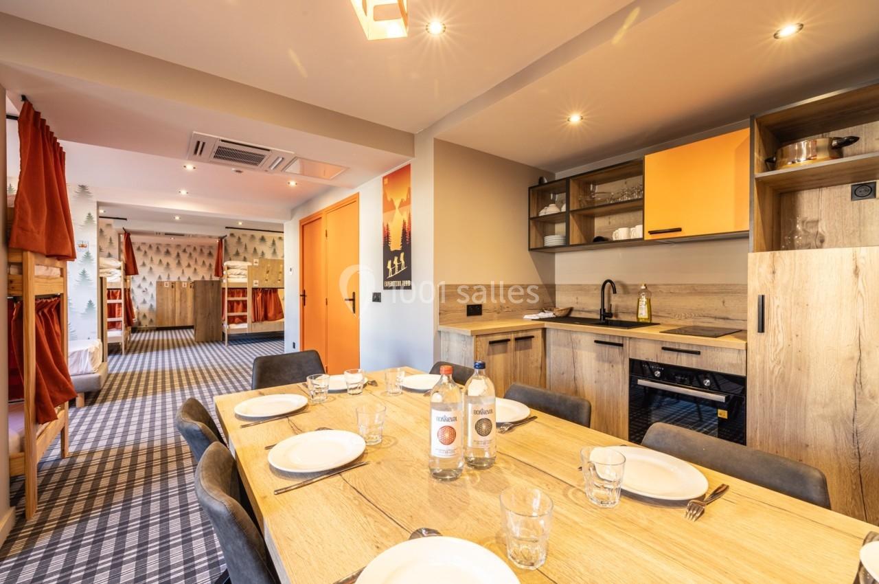 Cuisine ouverte avec table à manger dressée, vue sur un espace de vie avec lits superposés en arrière-plan.