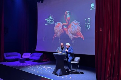 Un groupe de musiciens joue sur scène devant un écran affichant le logo et le slogan ’Base Camp Lodge’.