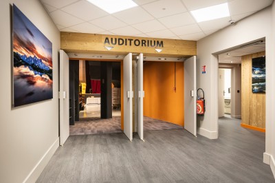 Un groupe de musiciens joue sur scène devant un écran affichant le logo et le slogan ’Base Camp Lodge’.