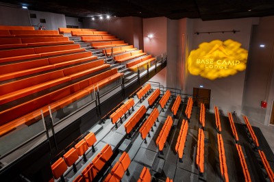 Un groupe de musiciens joue sur scène devant un écran affichant le logo et le slogan ’Base Camp Lodge’.