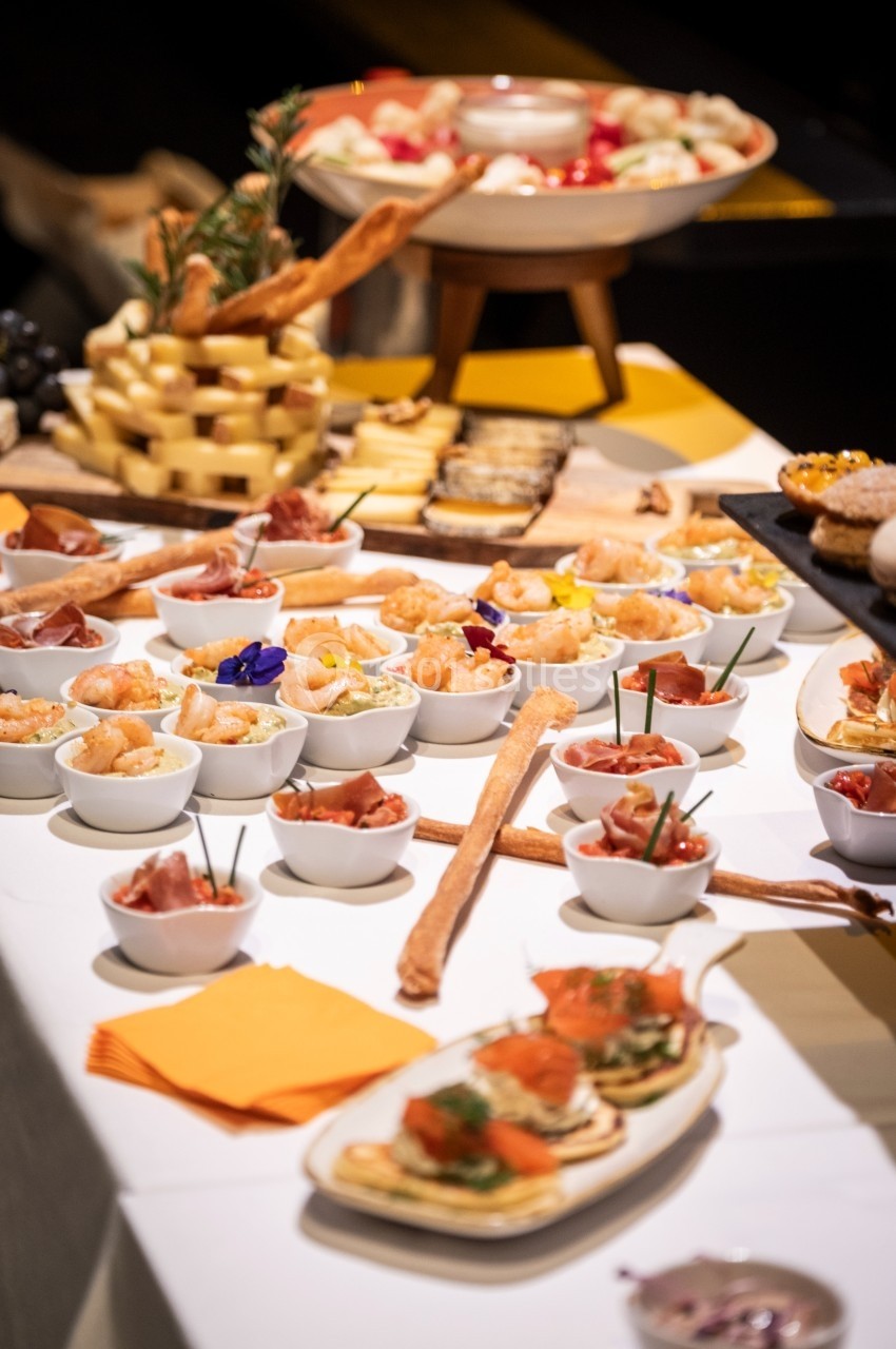 Buffet avec verrines, canapés, fromages et pains disposés sur une table blanche.
