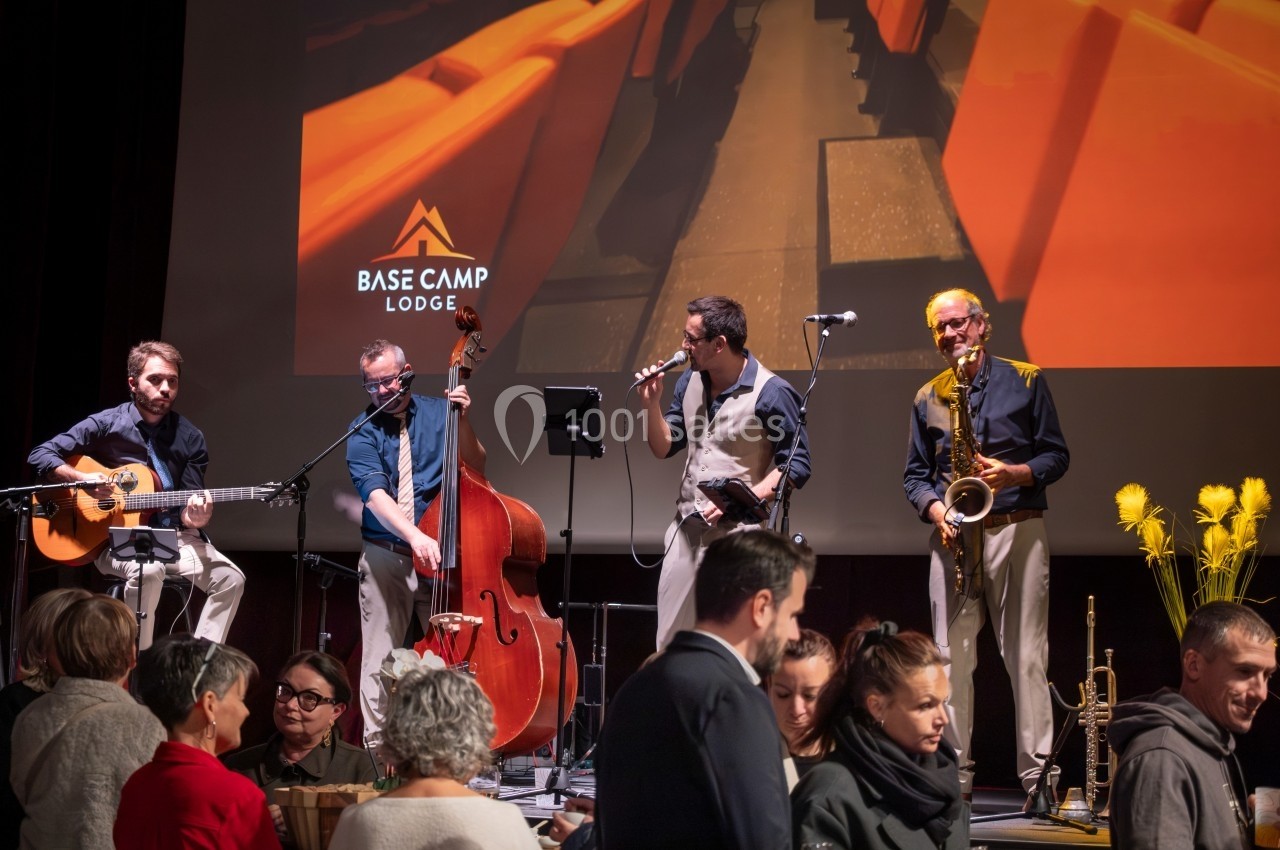 Un groupe de musiciens joue sur scène avec des instruments devant un public dans une salle de spectacle.