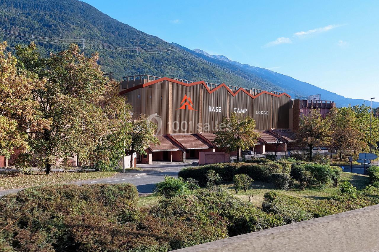 Bâtiment du Base Camp Lodge entouré de végétation, avec des montagnes en arrière-plan sous un ciel dégagé.