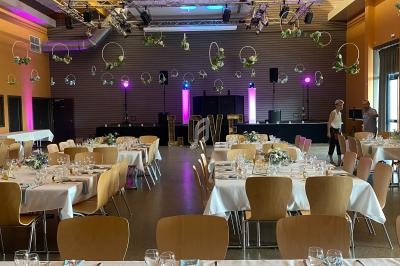 Salle décorée pour un événement avec tables dressées, centre de table floral et lettres géantes formant ’LOVE’.