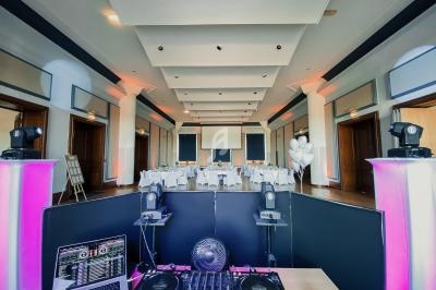 Salle de réception élégante avec tables dressées, vue depuis une console de DJ équipée de matériel audio et d'éclairage.