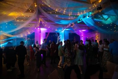 Groupe de personnes dansant sous un plafond décoré de voilages et de guirlandes lumineuses dans une ambiance tamisée.