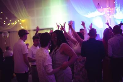 Salle de réception élégante avec tables rondes dressées, décorations florales et lumière naturelle entrant par les fenêtres.